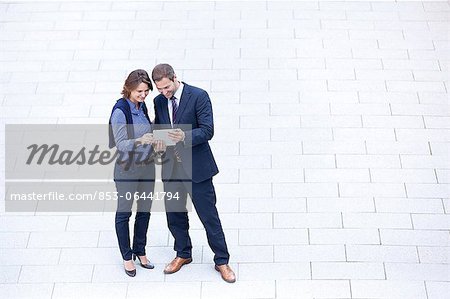 Businessman and businesswoman standing with tablet pc outdoors