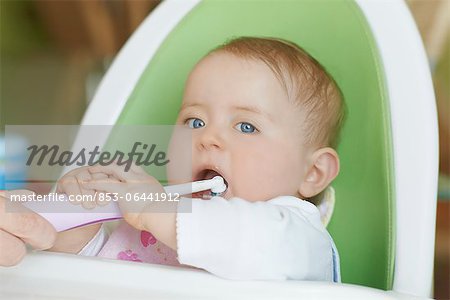 Female baby in highchair brushing teeth