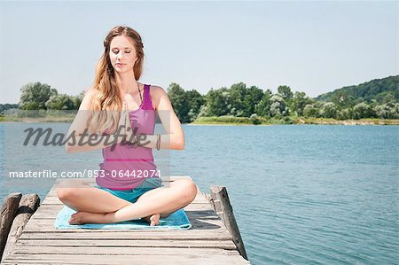 Blonde junge Frau praktizieren Yoga am See