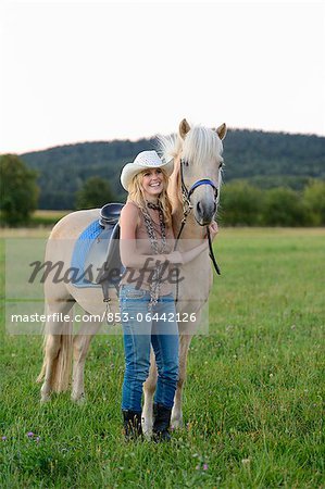 Lächelnde Frau mit Pferd auf der Wiese