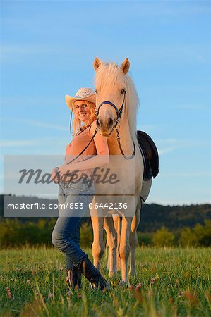 Femme souriante à cheval sur la prairie