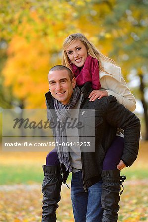 Man carrying woman piggyback in autumnal landscape