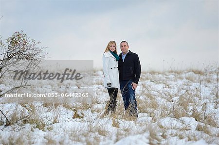 Couple standing on snowcapped meadow