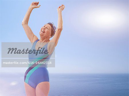 Senior woman wearing swimsuit cheering with arms raised