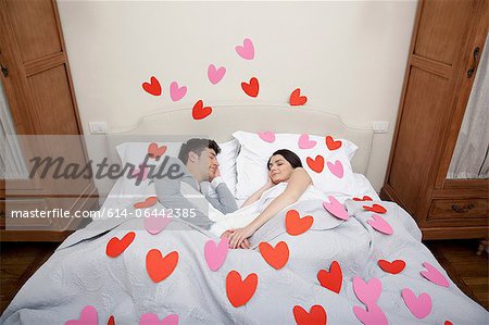 Couple au lit avec forme de coeur sur la literie