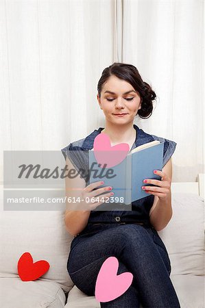 Young woman reading book with heart shapes