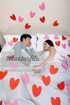 Couple in bed with heart shapes on bedclothes