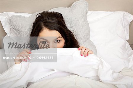 Woman peeking behind duvet