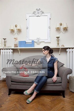 Woman on sofa picking up telephone handset
