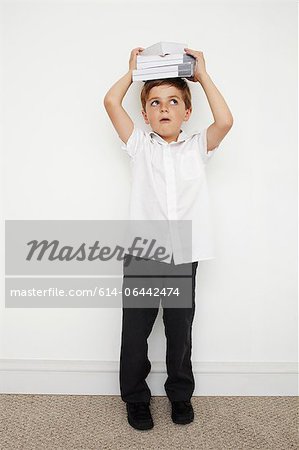 Schoolboy holding books on his head