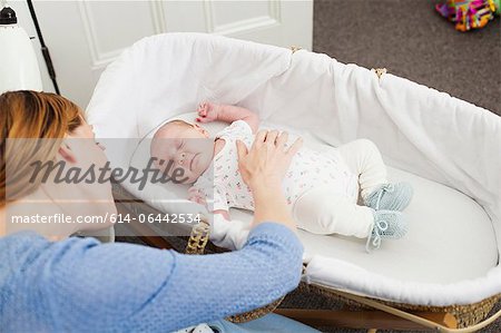 Mother comforting newborn daughter in bassinet