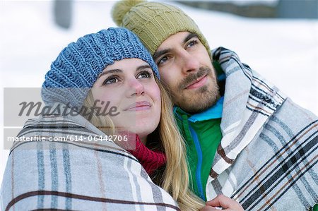 Portrait de couple portant des chapeaux, enveloppé dans une couverture en tricot