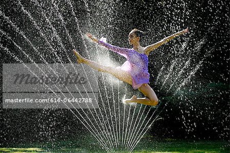 Ballerina jumping over water sprinkler