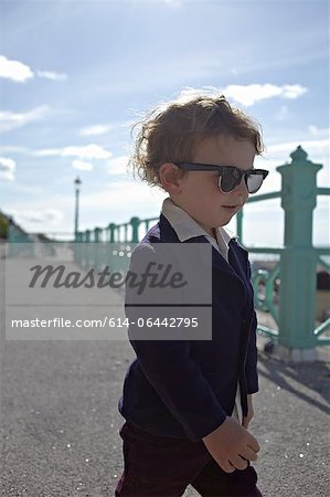 Petit garçon sur la promenade, porter des vêtements de style mod avec lunettes de soleil