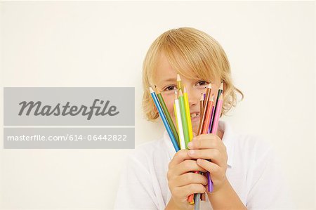 Schoolboy holding bunch of colouring pencils