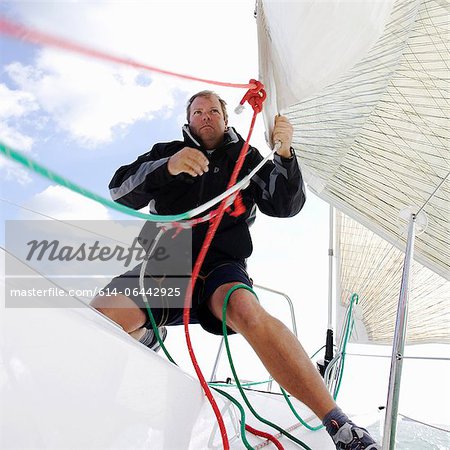 Homme sur yacht, tirant des cordes