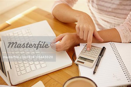 Woman using calculator with laptop