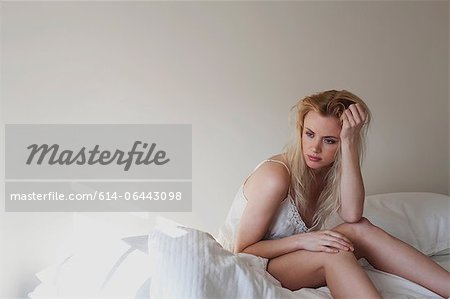 Aufgeregt junge Frau sitzt auf dem Bett