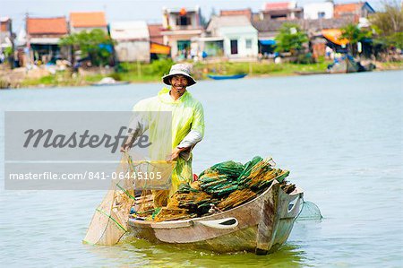 L'homme pêche depuis son bateau à la vieille ville de port de Hoi An, Vietnam, Indochine, l'Asie du sud-est, Asie