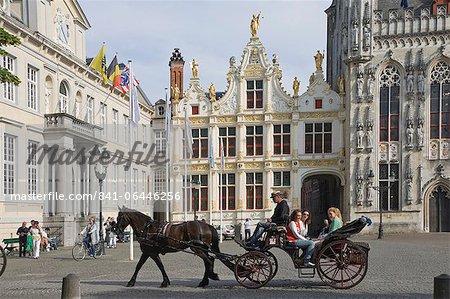 A horse drawn carriage crosses the Burg Square, passing the Stadhuis (Town Hall) buildings, Brugge, Belgium, Europe