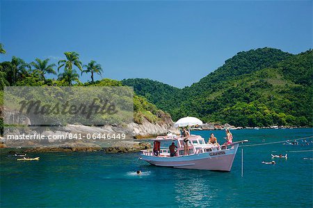 Tourist on a chartered fishing boat cruising between the different beaches and islands around Parati, Rio de Janeiro State, Brazil, South America
