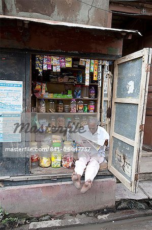 Propriétaire d'une boutique lisant le journal dans la matinée, Kolkata, West Bengal, Inde, Asie