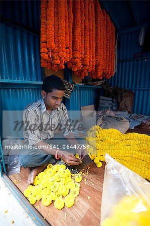 Mala-Hersteller (Girlande-Hersteller) bei der Arbeit mit orange und gelbe Ringelblumen in Morgen Blume Markt, Howrah, Kalkutta, Westbengalen, Asien