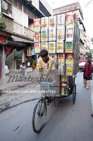 Cycle rickshaw carrying huge load of oil cans through market, Kolkata (Calcutta), West Bengal, India, Asia