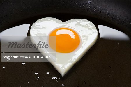 heart shaped egg cooking in a frying pan