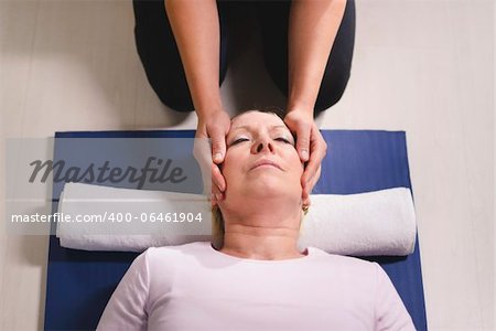 Alternative traditional medicine and massage, young spirit healer doing reiki treatment to old woman. High angle view, head and shoulders