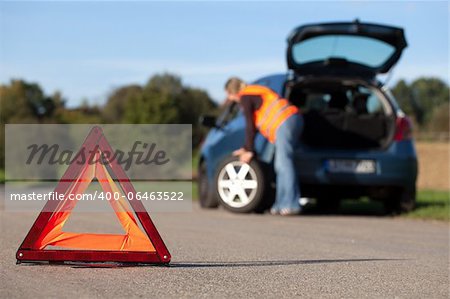 Tire change on a broken down car with a red warning triangle