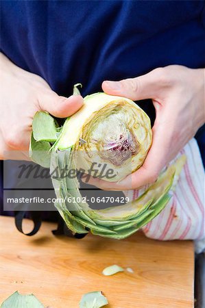 Man peeling off an artichoke.