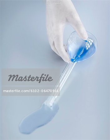 Hand in surgical glove holding laboratory flask