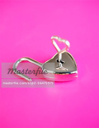 Close-up of small heart shaped padlock on pink background