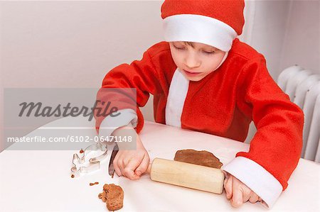 Boy wearing Santa hat preparing gingerbread