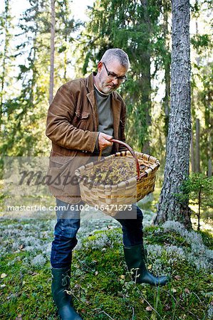 Mature man with basket full of mushrooms