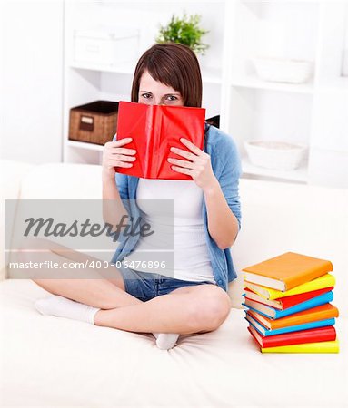 Girl hiding behind book on the sofa