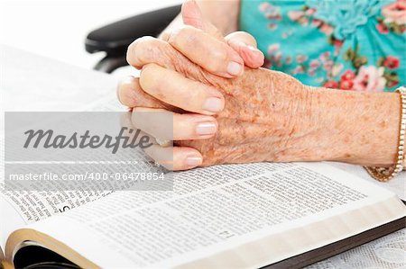 Closeup of senior woman's hands on bible, folded in prayer.