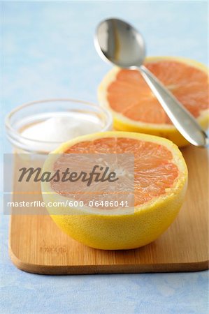 Close-up of Grapefruit cut in half with Bowl of Sugar and Spoon on Cutting Board, Studio Shot