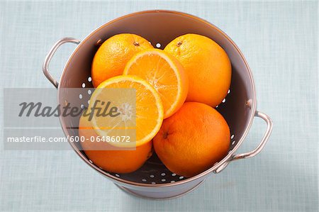 Overhead View of Oranges in Colander on Blue Background, Studio Shot