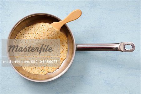 Overhead View of Pancake in Frying Pan with Spatula on Blue Background, Studio Shot