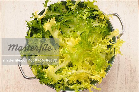 Overhead View of Lettuce in Colander for Salad on Beige Background, Studio Shot