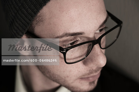 Close-up, High Angle View of Young Man wearing Woolen Hat and Eyeglasses, Studio Shot