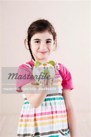 Portrait of Girl holding Piggy Bank in Studio