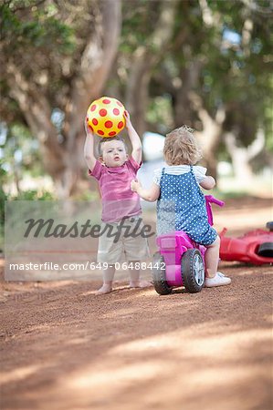 Toddlers playing together on dirt road