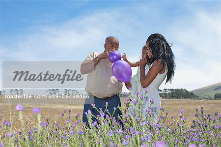 Family playing with balloons in field