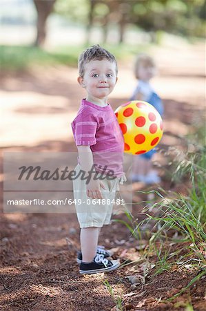 Toddler boy with ball on dirt road