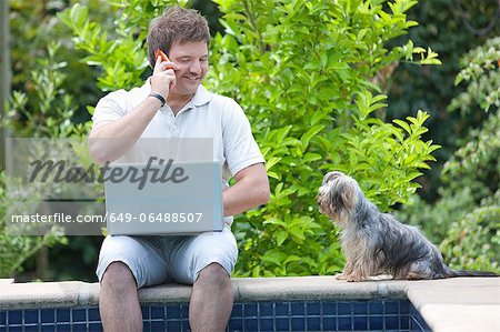 Man using cell phone and laptop outdoors