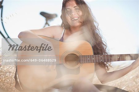 Woman playing guitar in tall grass