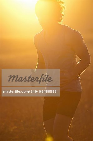 Man running in tall grass at sunset